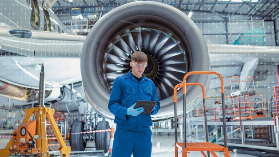 Airplane maintenance worker standing in front of jet engine with 1s and 0s overlaid on top.